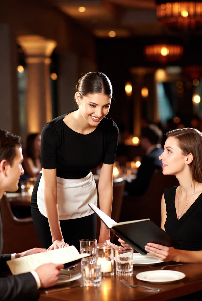 Restaurant staff preparing for service in a dimly lit dining room